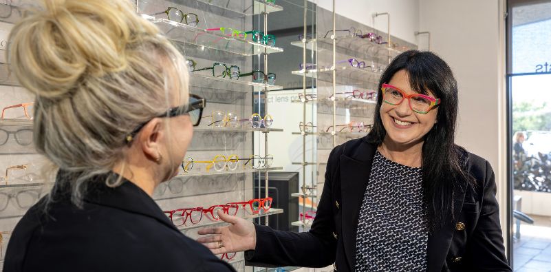 A customer trying on a colourful frame and looking extremely happy