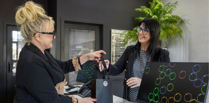 A patient collecting newly fitted prescription glasses from Optomed Optometrists